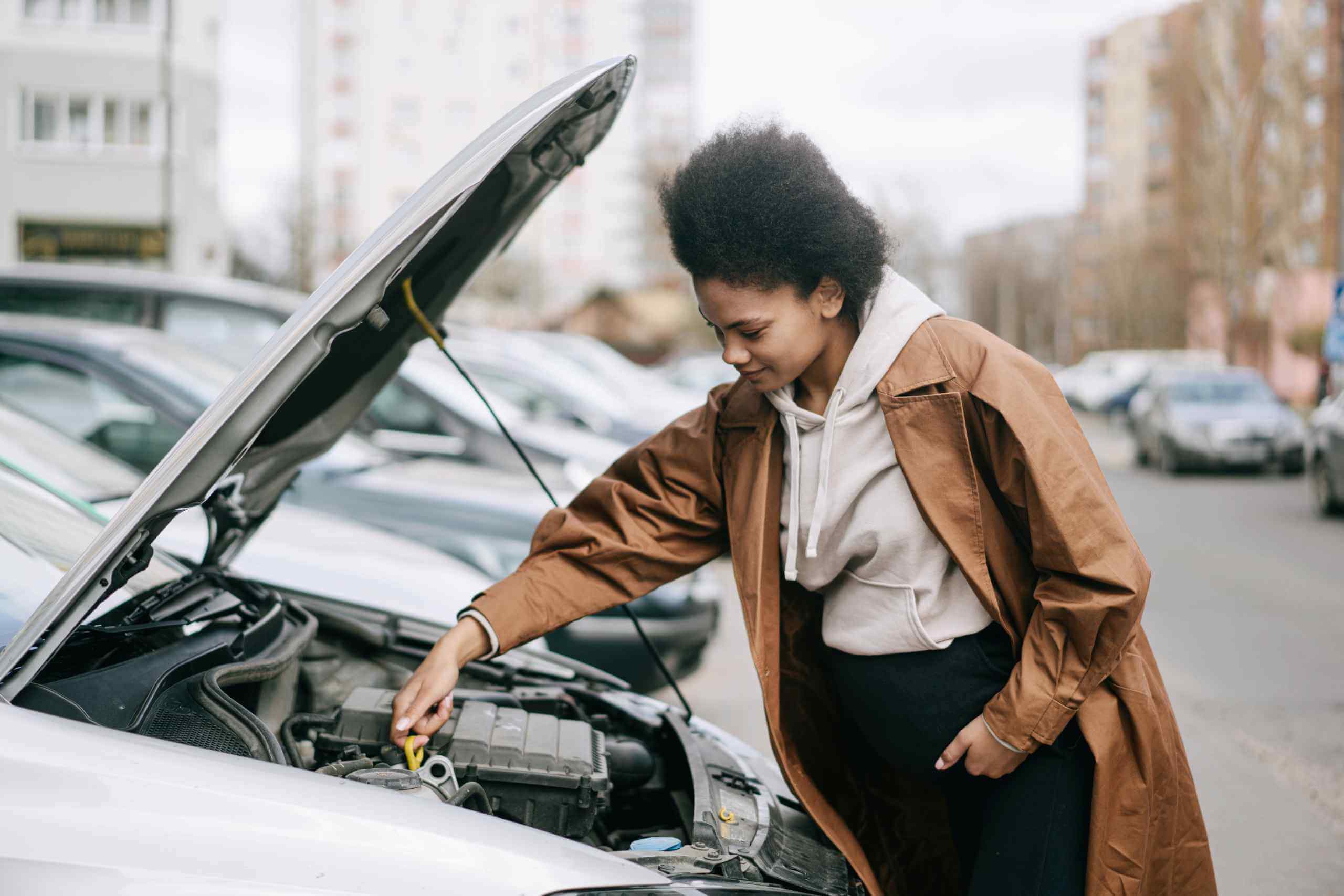 Woman Inspecting The Oil Dipstick of a Car
