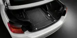  A photo of the trunk of a white BMW 4 Series Convertible. The boot is empty and has a black cargo liner. The taillight is visible in the background.