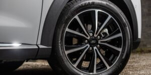 Close-up view of a car's front wheel and tire. The wheel features a black and silver alloy rim with a multi-spoke design. The tire is a Goodyear brand, with visible tread and sidewall details. Part of the car's silver body and lower panel is also visible.