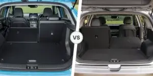 A side-by-side comparison of the cargo areas of the Hyundai Kona Electric and Kia e-Niro. The Hyundai Kona Electric has a more square-shaped boot area with a flat floor. The Kia e-Niro has a slightly more sloping cargo area with a deeper shape. Both cars have rear seats that can be folded down to increase boot space.