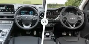 A side-by-side comparison of the interiors of the Hyundai Kona Electric and Kia e-Niro. The Hyundai Kona Electric interior features a large touchscreen display and a digital instrument cluster. The Kia e-Niro interior has a simpler design with a smaller touchscreen display and analog gauges. Both cars have black leather seats and a similar steering wheel design.