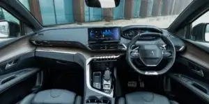 The interior of a Peugeot 3008 SUV. The car has a modern and stylish design with a large touchscreen display, a small steering wheel, and comfortable-looking leather seats.