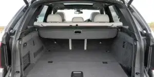 The open boot of a BMW X5 SUV. The boot is empty and has a spacious interior with a flat load floor. The rear seats are visible folded down, and there is a cargo cover in place.