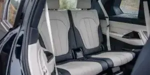 The third-row seats of a BMW X7 SUV. The seats are upholstered in a combination of black and white leather, and they have headrests with the BMW logo. The seats are spacious and offer ample legroom.