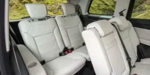 The image shows the interior of a Mercedes-Benz GLS, specifically the second-row seating. The seats are upholstered in white leather and appear to be very comfortable. There is ample legroom and headroom, even for taller passengers. The seats also have adjustable headrests and armrests.