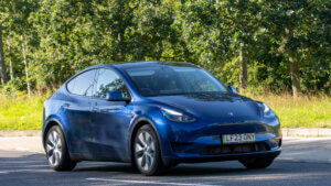 Blue 2023 Tesla Model Y RWD electric car driving on an English country road.