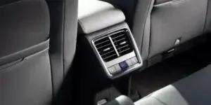 A close-up of the rear seat vents in a car. The vents are rectangular and have multiple openings. There is a control panel below the vents with buttons for adjusting the airflow and temperature.