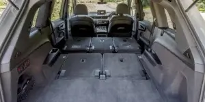 The cargo area of an Audi Q7 SUV with the second and third-row seats folded down. The cargo area is spacious and has a flat load floor. The seats are folded down and secured by straps.