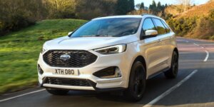 A white Ford Edge driving on a winding road.