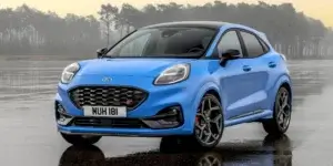 A blue Ford Puma ST parked on a wet road.