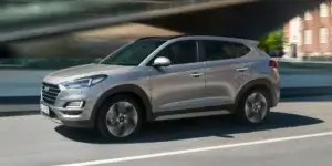 Silver Hyundai Tucson driving on a city street.