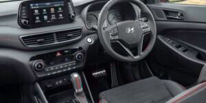 Interior of a Hyundai Tucson showing the dashboard, steering wheel, gear shift, and center console.