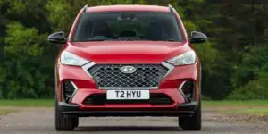 Red Hyundai Tucson parked on a road with trees in the background.