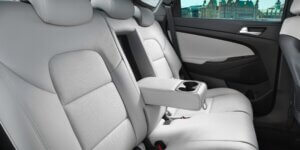 Backseat of a Hyundai Tucson showing two white leather seats with a center armrest and cup holders.